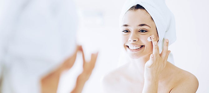 Benefits of Clean Skin—ageLOC LumiSpa A young girl looks in the mirror as she applies a skin cleanser to her face